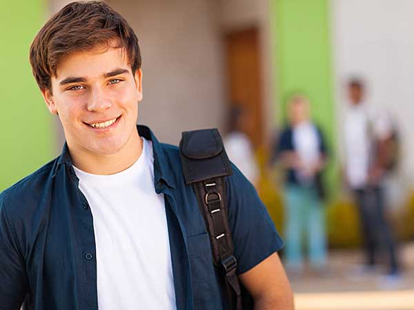 Teen boy carrying schoolbag.